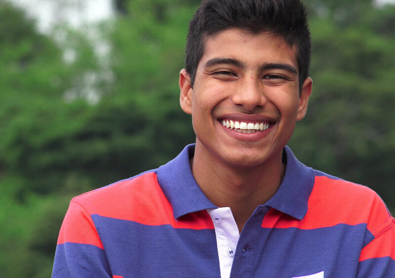 Happy young man smiling outside in striped shirt