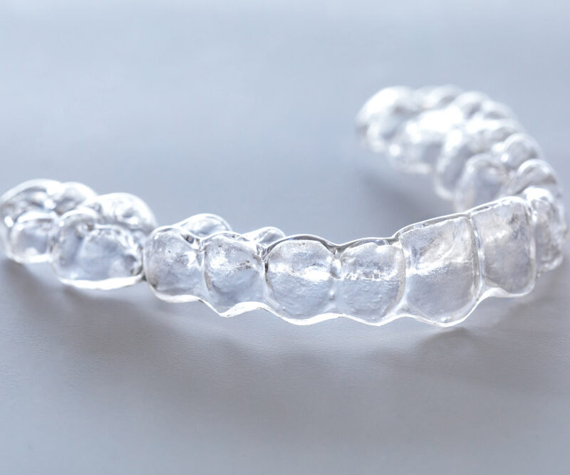 Clear dental aligner on a gray background. invialign