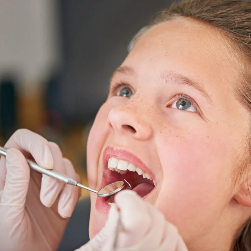 Young girl receiving early orthodontic evaluation, smiling